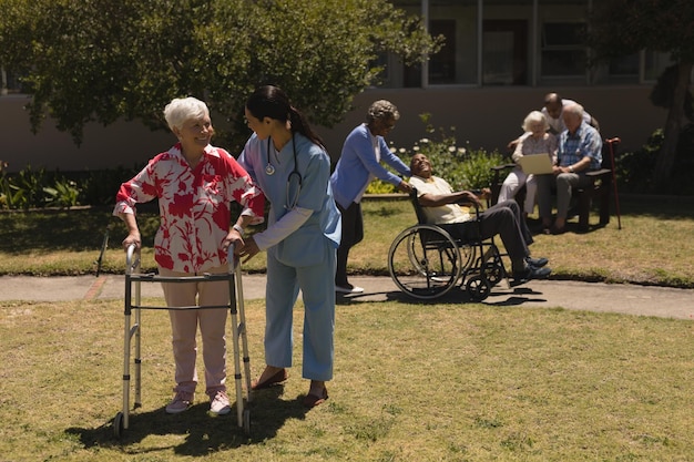Photo une jeune médecin aidant une femme âgée handicapée dans le jardin