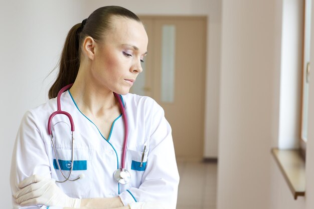 Un jeune médecin après une journée de travail stressante reste dans le couloir d'un hôpital.