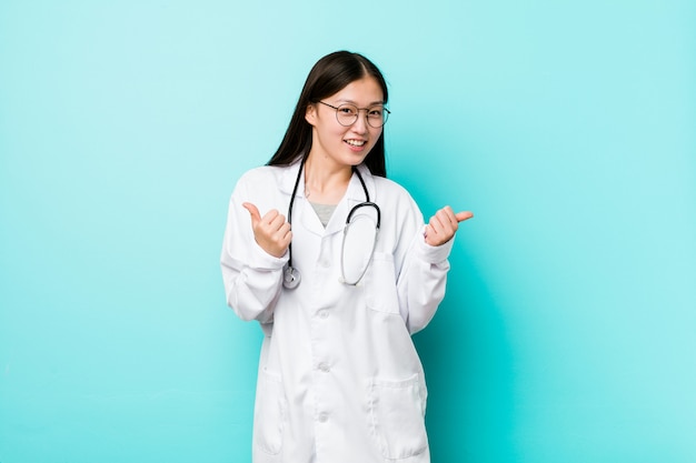 Jeune médecin chinois femme levant les deux pouces, souriant et confiant.