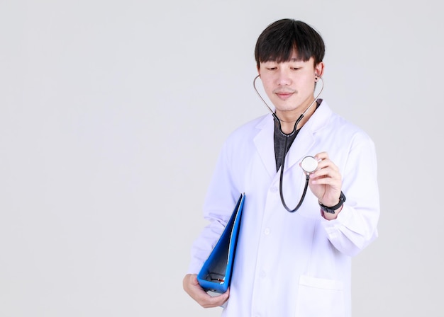 Jeune médecin chinois intelligent sur robe médicale professionnelle avec stéthoscope sourire avec confiance et heureux de réussir le traitement de la maladie avec coffre-fort. Docteur heureux et assurer les soins de santé.