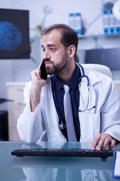 Jeune médecin consultant un collègue par téléphone concernant une lésion cérébrale. Médecin utilisant un smartphone.