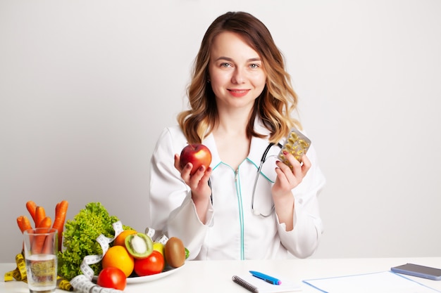 Jeune médecin diététiste au cabinet de consultation à table avec des fruits et légumes frais