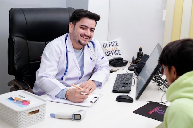 Un jeune médecin est assis dans une clinique en train de parler avec un patient et souriant