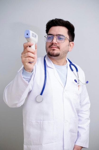 Photo un jeune médecin est debout et tient un thermomètre numérique à la main