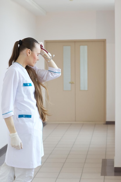 Un jeune médecin généraliste stressé reste dans le couloir d'un hôpital.