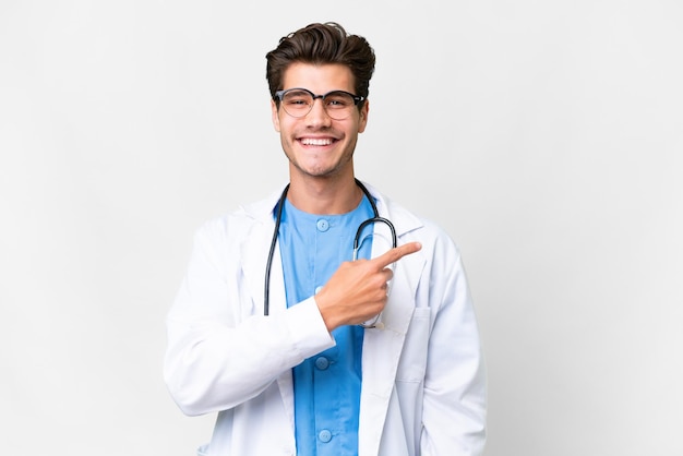 Jeune médecin homme sur fond blanc isolé pointant vers le côté pour présenter un produit