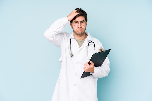 Jeune médecin homme isolé sur un mur bleu choqué, elle s'est souvenue d'une réunion importante.