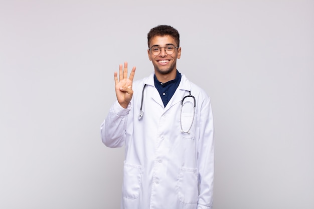 Jeune médecin homme souriant et à la sympathique, montrant le numéro quatre ou quatrième avec la main en avant, compte à rebours
