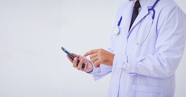 Jeune médecin homme vêtu d&#39;une blouse blanche à l&#39;aide d&#39;un smartphone