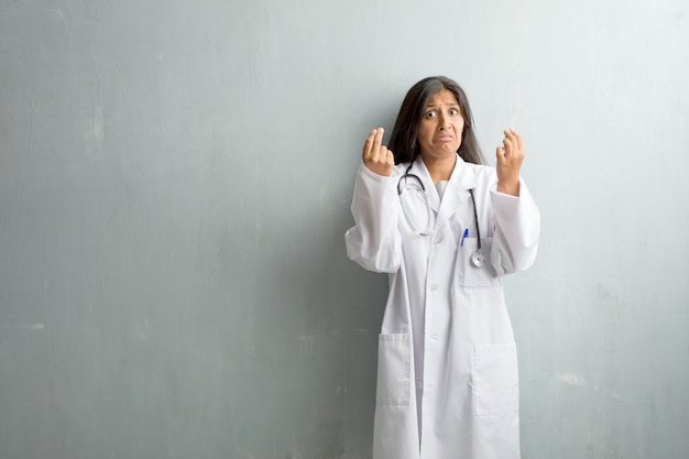 Jeune médecin indien femme contre un mur triste et déprimé, faisant un geste de nécessité, restaurant à la charité, concept de pauvreté et de misère