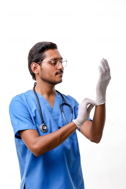 Jeune médecin indien mettant des gants de protection isolés sur fond blanc.