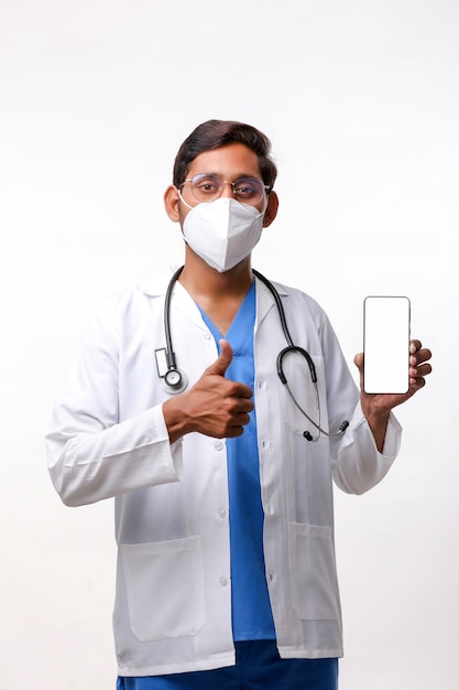 Jeune médecin indien montrant l'écran du smartphone sur fond blanc.