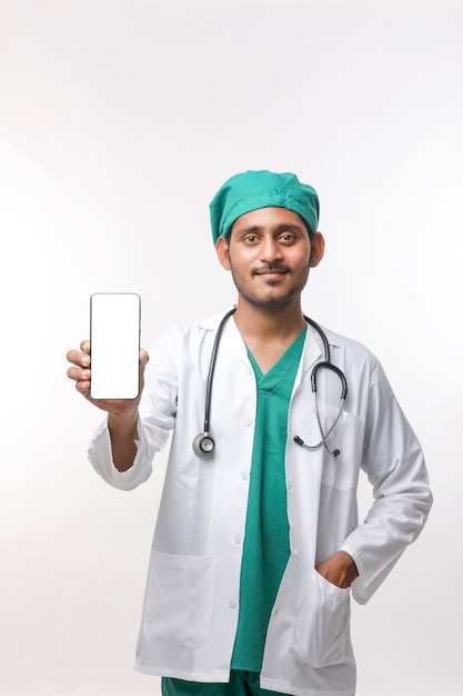 Jeune médecin indien montrant l'écran du smartphone sur fond blanc.