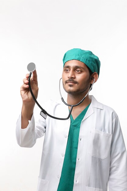 Jeune médecin indien tenant un stéthoscope à la main sur fond blanc.