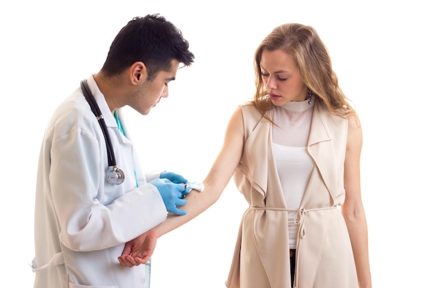 Jeune médecin intelligent avec stéthoscope faisant une injection de belle jeune femme