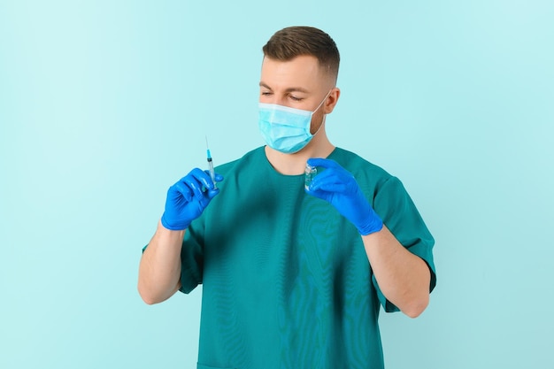 Jeune médecin en masque médical et blouse blanche avec stéthoscope tenant une seringue isolée sur bleu