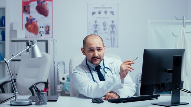 Jeune médecin offrant des conseils médicaux sur Internet dans le bureau d'une clinique privée moderne. Médecin utilisant la technologie Internet pour consulter les patients pendant la pandémie mondiale de covid-19. Télémédecine et santé