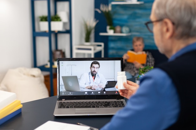 Jeune Médecin Parlant Du Traitement Avec Un Homme âgé Lors D'un Examen Virtuel