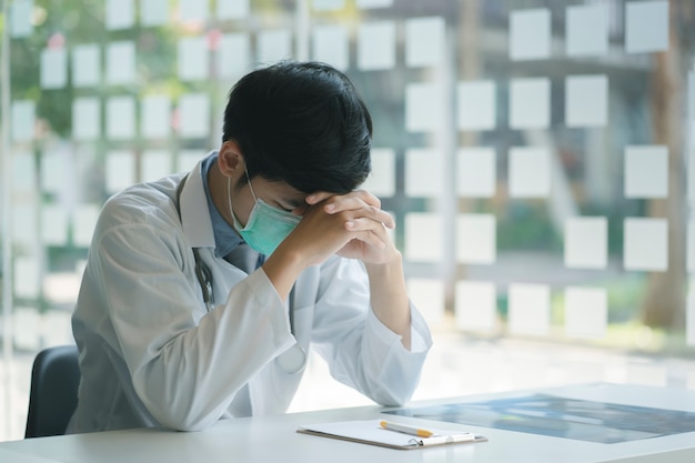 Jeune médecin portant un stéthoscope stressé avec des migraines surmenées et du stress.