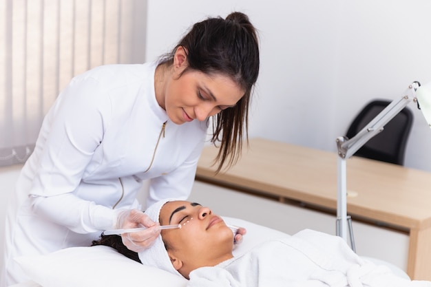 Jeune médecin prenant soin d'une femme âgée dans le parc. Médecin écoutant le cœur d'une femme âgée. Les deux avec masque