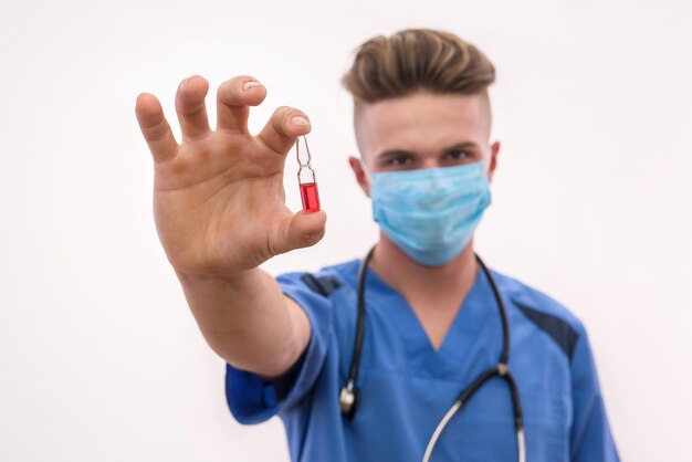 Jeune médecin réfléchi regardant le tube à essai rouge. Il le tient isolé sur fond blanc