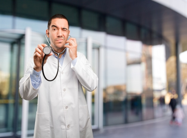 Un jeune médecin réfléchi utilisant un stéthoscope