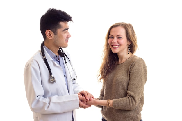 Jeune médecin séduisant en robe blanche avec stéthoscope sur son cou embrassant une jeune jolie femme