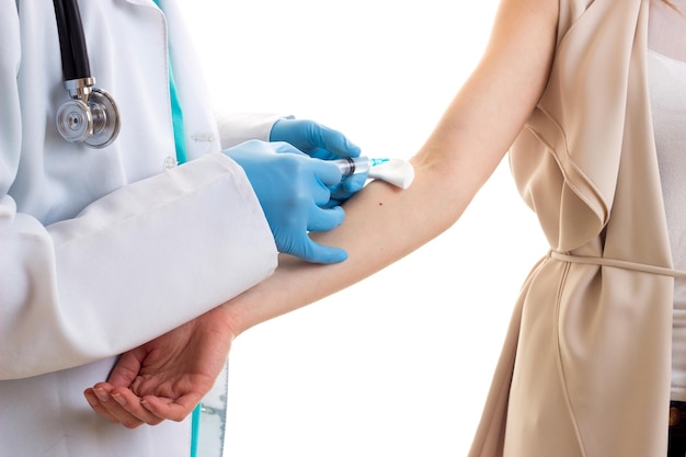 Jeune médecin sérieux en robe blanche avec stéthoscope faisant une injection de jeune femme effrayée