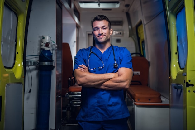 Photo jeune médecin souriant dans un uniforme bleu debout et regardant la caméra.