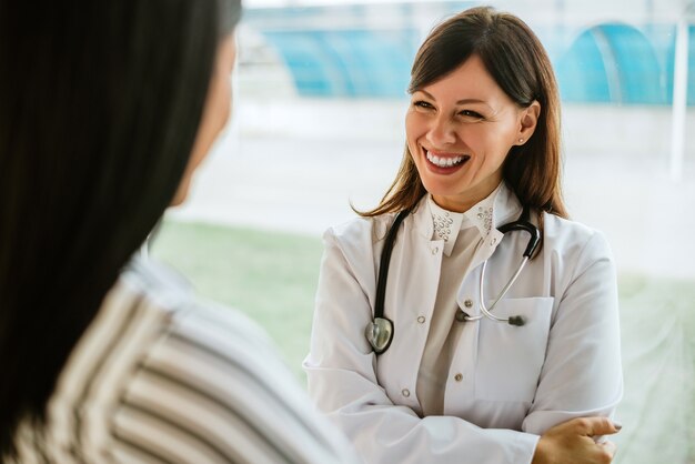 Jeune médecin souriant parlant avec un patient au bureau