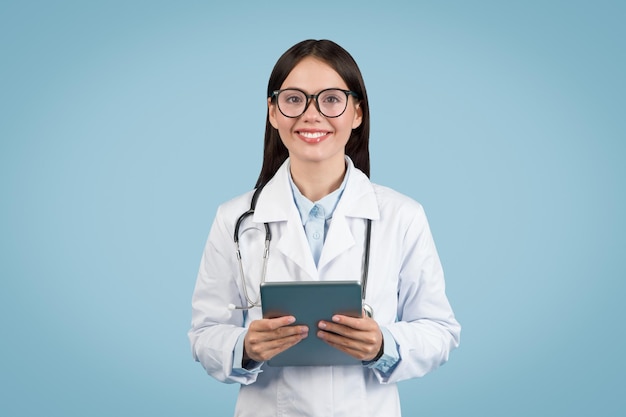 Une jeune médecin souriante avec une tablette souriant à la caméra.