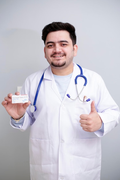 Photo un jeune médecin tient un médicament dans une main et montre un signe de pouce levé