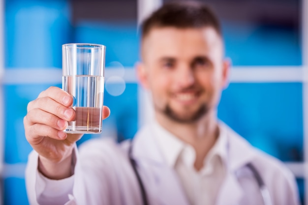 Jeune médecin tient un verre d'eau.