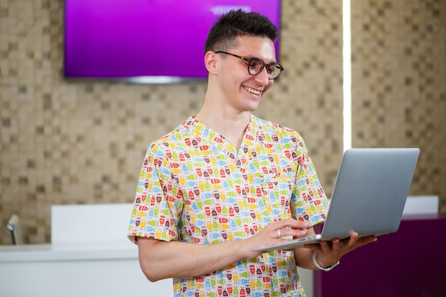 Un jeune médecin travaille sur un ordinateur portable sur une thèse. Le médecin de la clinique procède à l'accueil des patients en ligne