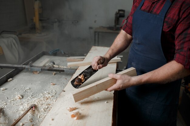 Jeune menuisier avec un tablier dans son atelier