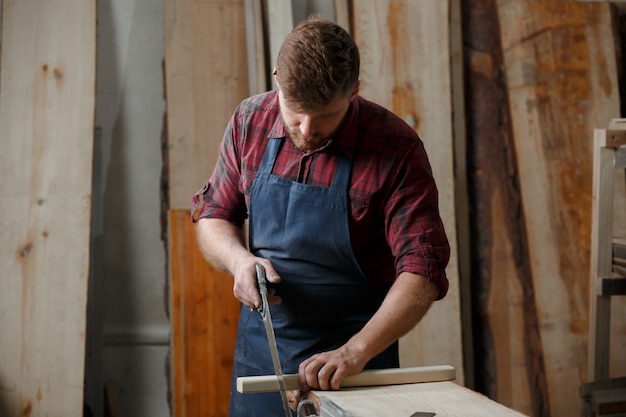 Jeune menuisier avec un tablier dans son atelier