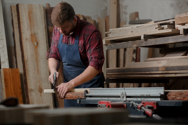 Jeune menuisier avec un tablier dans son atelier