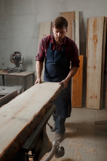 Jeune menuisier avec un tablier dans son atelier