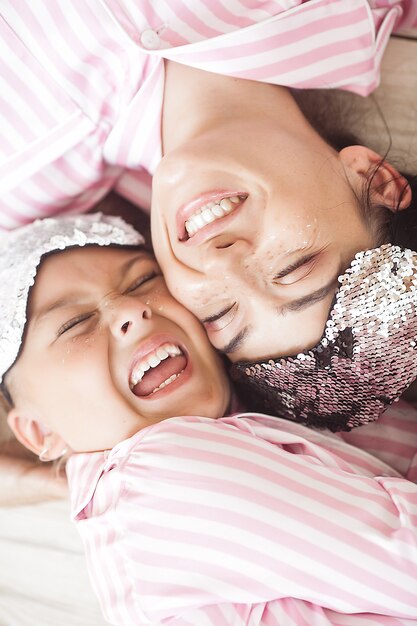 Jeune mère active et sa petite fille s'amusant ensemble à la maison dans la chambre en pyjama