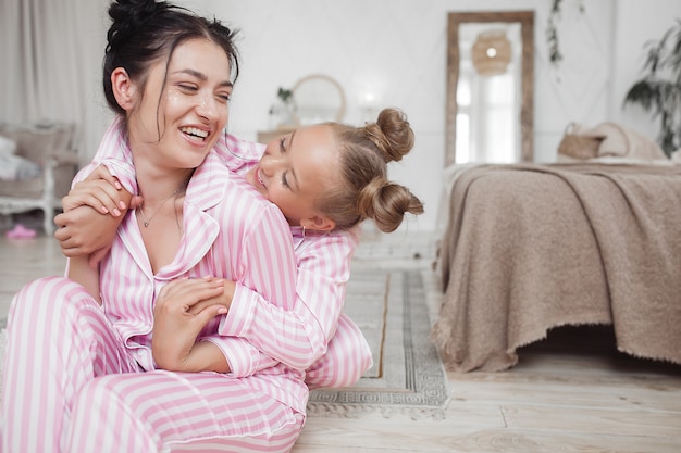 Jeune mère active et sa petite fille s'amusant ensemble à la maison dans la chambre en pyjama