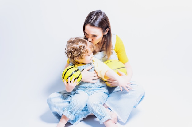 Jeune Mère Adulte Monoparentale Jouant Avec Son Fils Avec Un Ballon De Basket-ball Et De Football