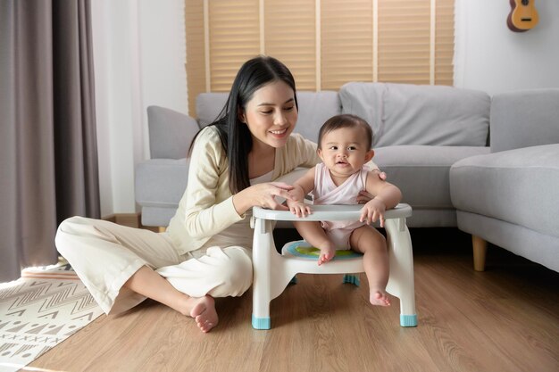 Jeune mère aidant bébé à manger des aliments mélangés sur une chaise bébé