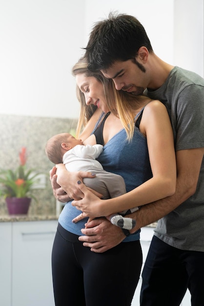 Jeune mère allaitant son fils dans la cuisine avec son père à ses côtés