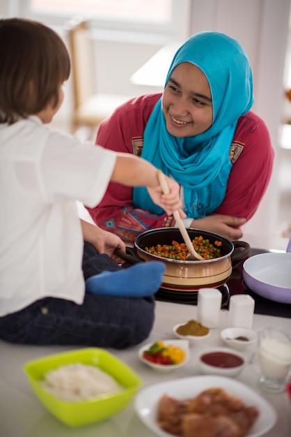 Photo jeune mère arabe musulmane et petit fils mignon faire de la nourriture et s'amuser dans la cuisine