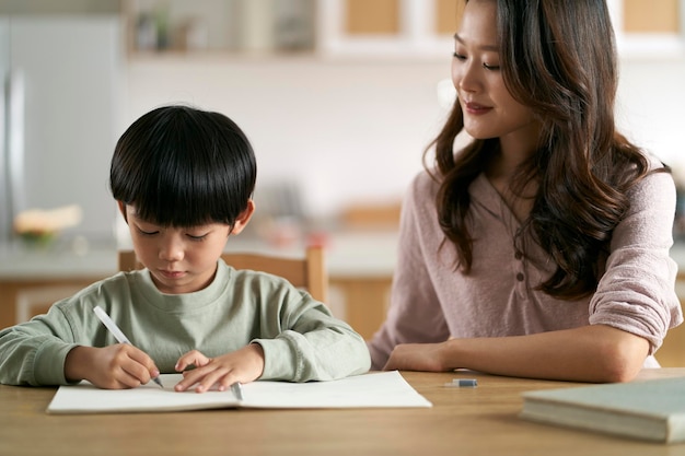 Une jeune mère asiatique aide son fils à faire ses devoirs.