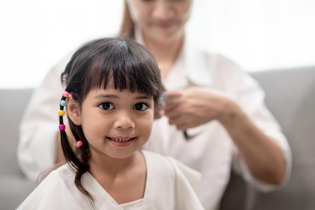 Jeune mère asiatique attachant les cheveux de sa fille