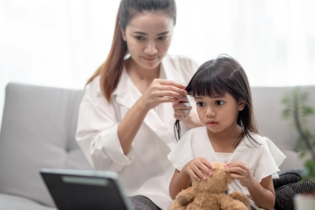 Jeune mère asiatique attachant les cheveux de sa fille