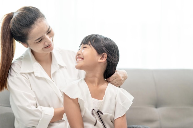 Jeune mère asiatique attachant les cheveux de sa fille