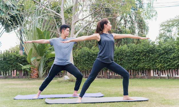 Une jeune mère asiatique, un père pratiquant des exercices de yoga avec sa fille enfant à l'extérieur en méditant posent ensemble dans la nature un parc de jardin sur le terrain, un sport familial pour enfants et des exercices pour un mode de vie sain