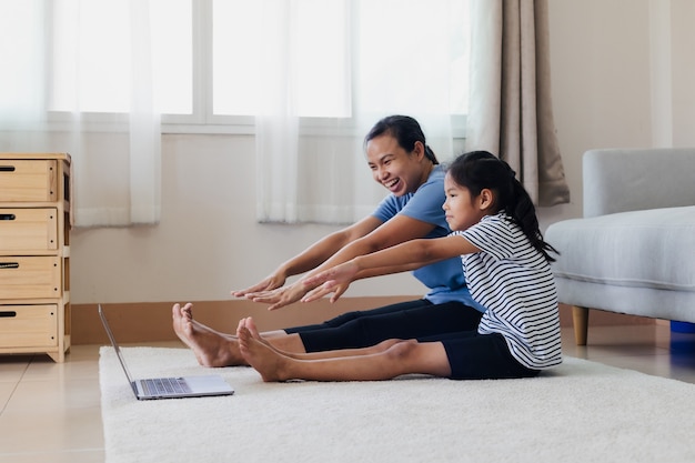 Jeune mère asiatique et sa fille faisant du yoga exercice de remise en forme étirement ensemble à la maison. Parent enseignant à l'enfant à travailler pour être fort et maintenir la santé physique et le bien-être dans la routine quotidienne.